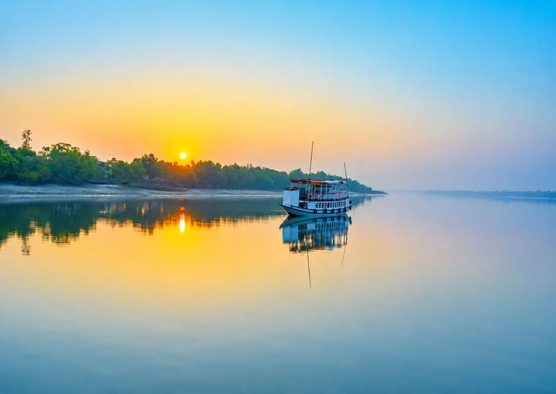 Tourist boat sailing through Sundarban river at sunrise representing Sundarban sightseeing tour operator